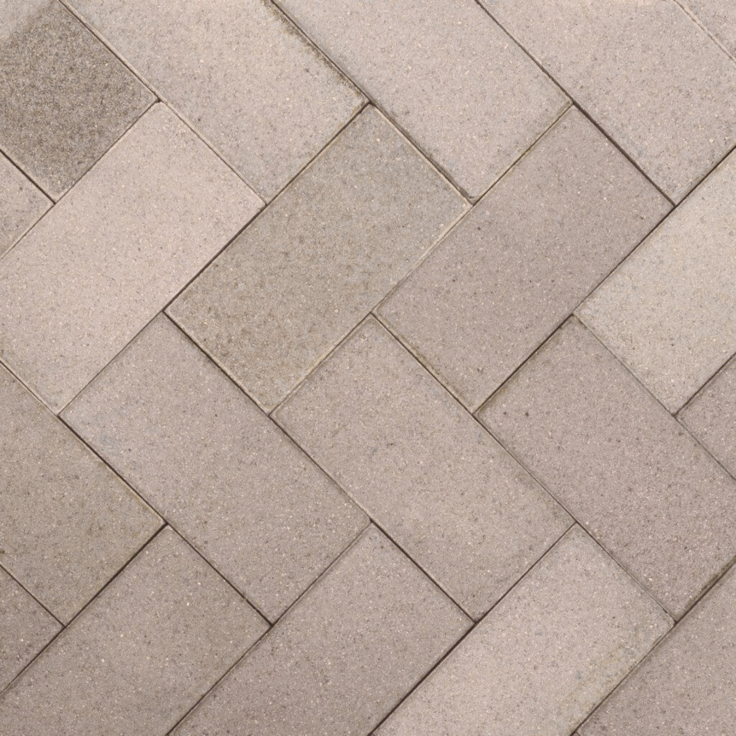 Pattern of beige stone tiles arranged in a herringbone design.