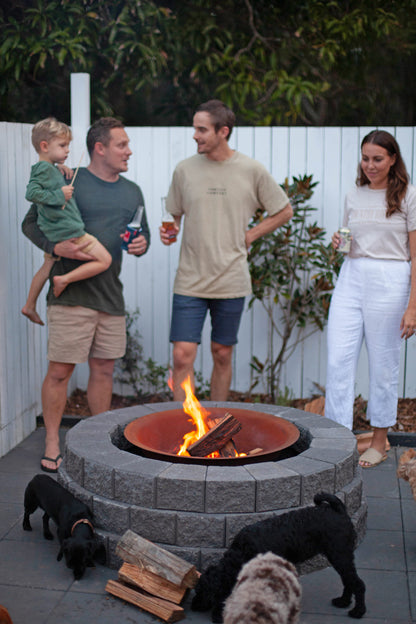Family and friends gathered around a fire pit in an outdoor setting