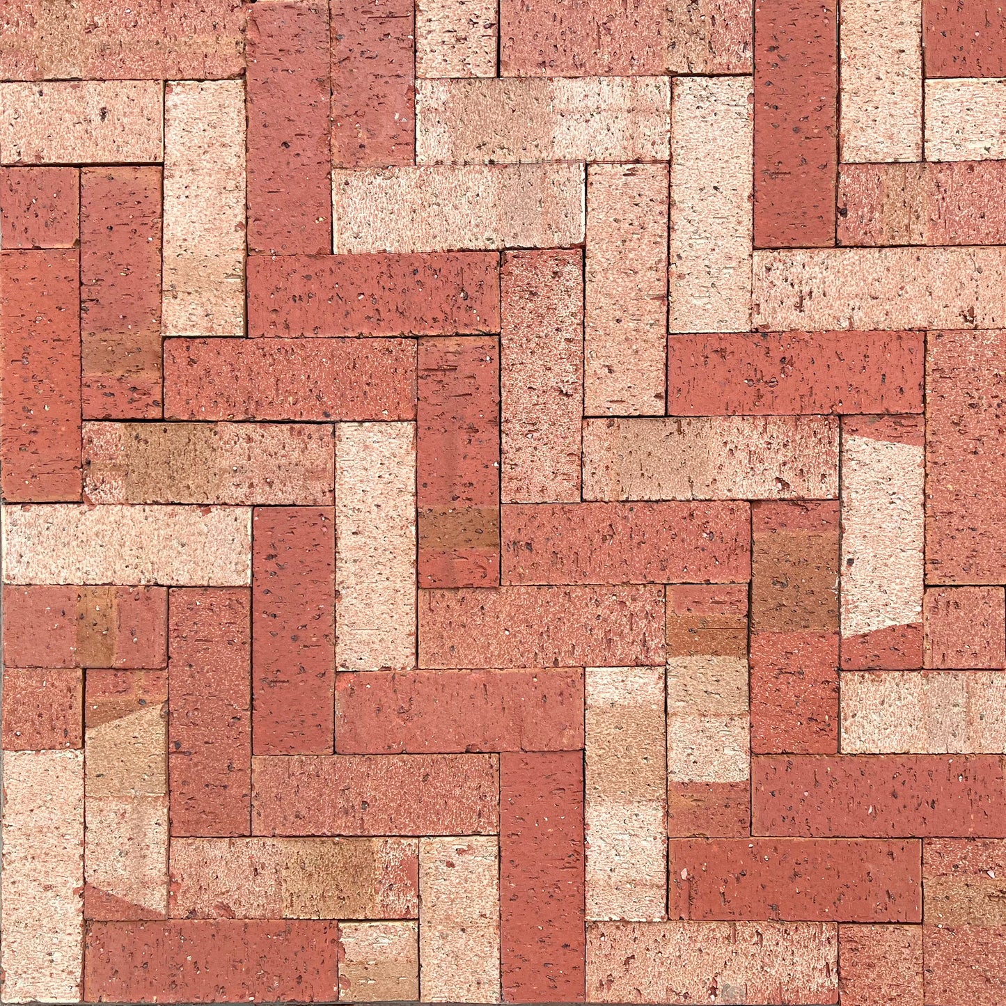 Pattern of red and beige bricks arranged in a herringbone pattern.