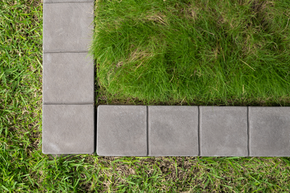 Gray concrete pavers forming a border around green grass