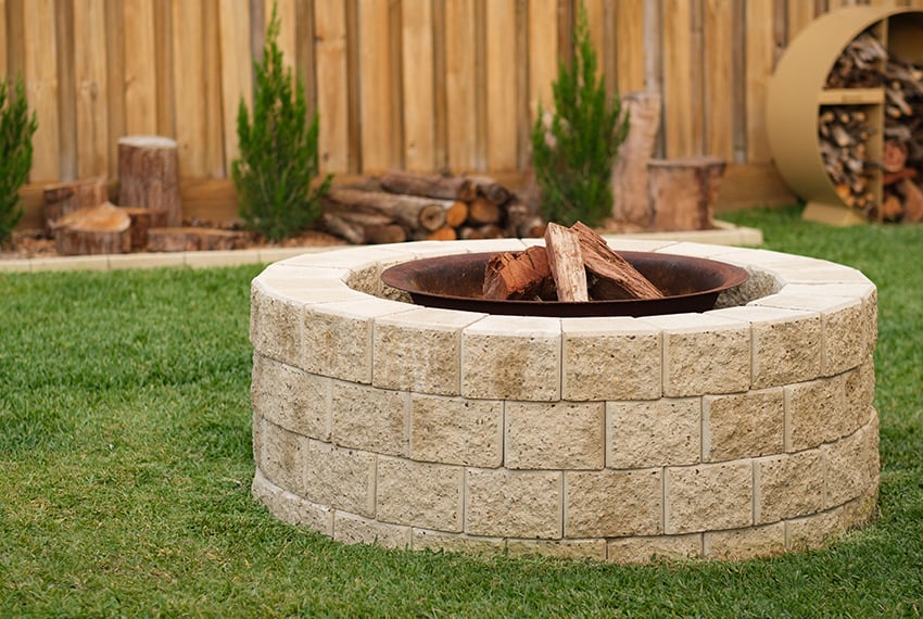 Stone fire pit with wooden logs in a backyard setting