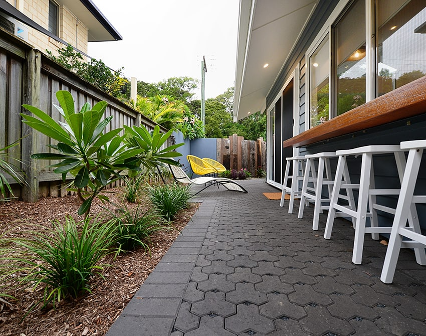 Outdoor patio area with plants, chairs, and a counter.