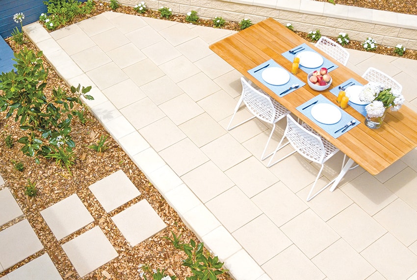 Outdoor dining setup with a wooden table and white chairs on a patio.