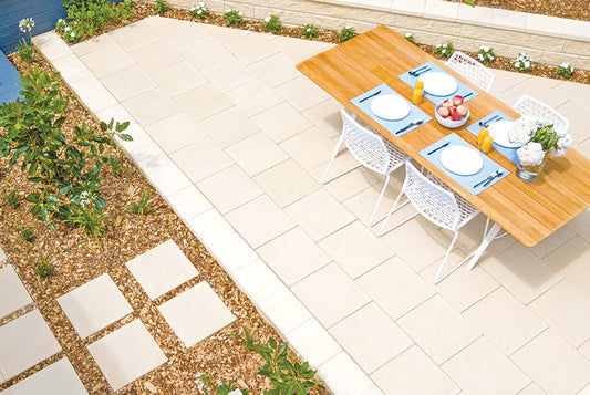 Outdoor dining setup with a wooden table and white chairs on a patio.