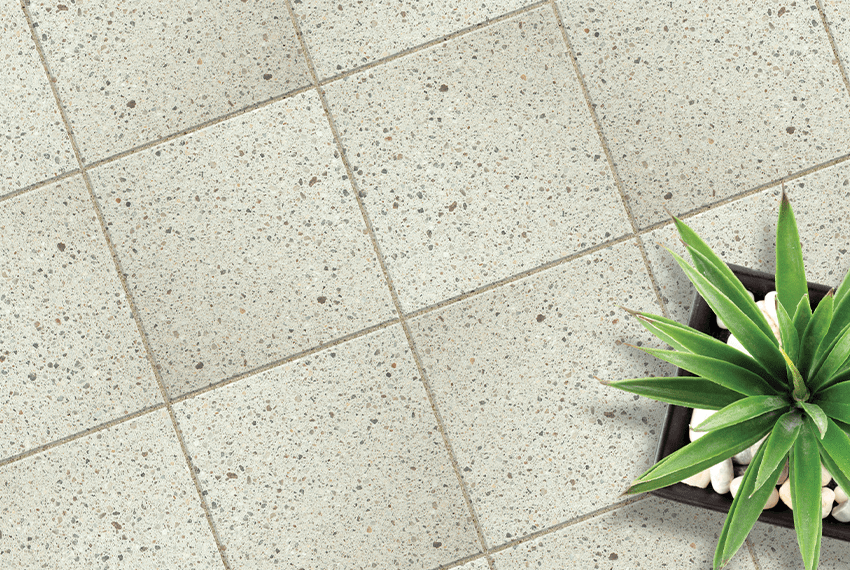 Gray tiled floor with a small plant and decorative stones.
