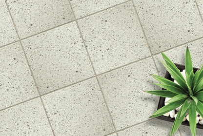 Gray tiled floor with a small plant and decorative stones.