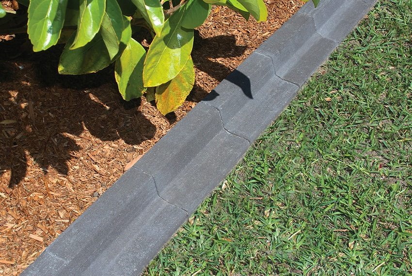 Gray stone border along a grassy area with plants