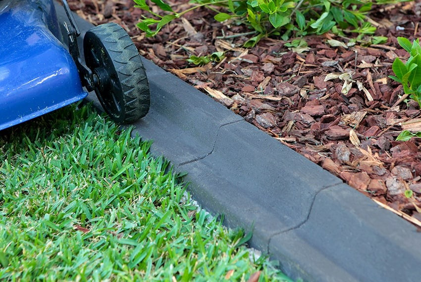 Lawn mower cutting grass along a black border