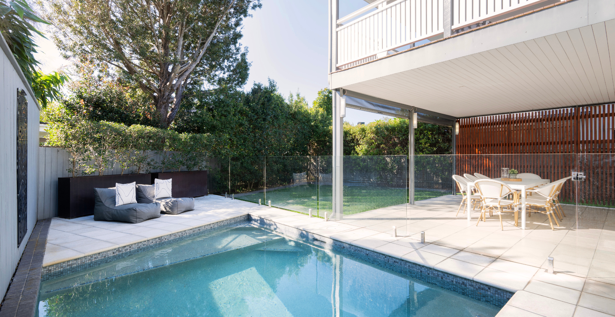 Modern outdoor area with pool, seating, and dining furniture.