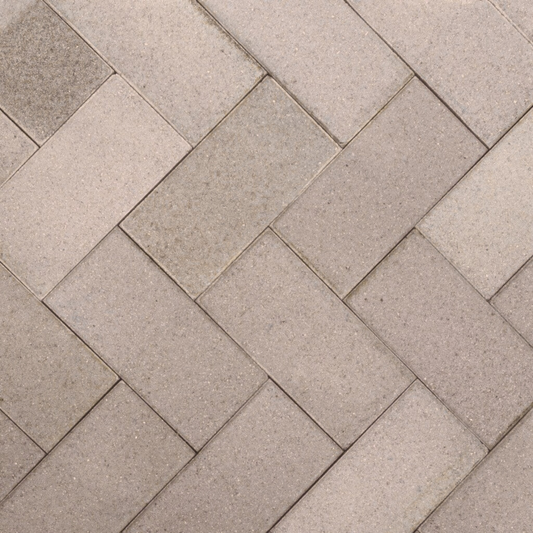 Pattern of beige stone tiles arranged in a herringbone design.