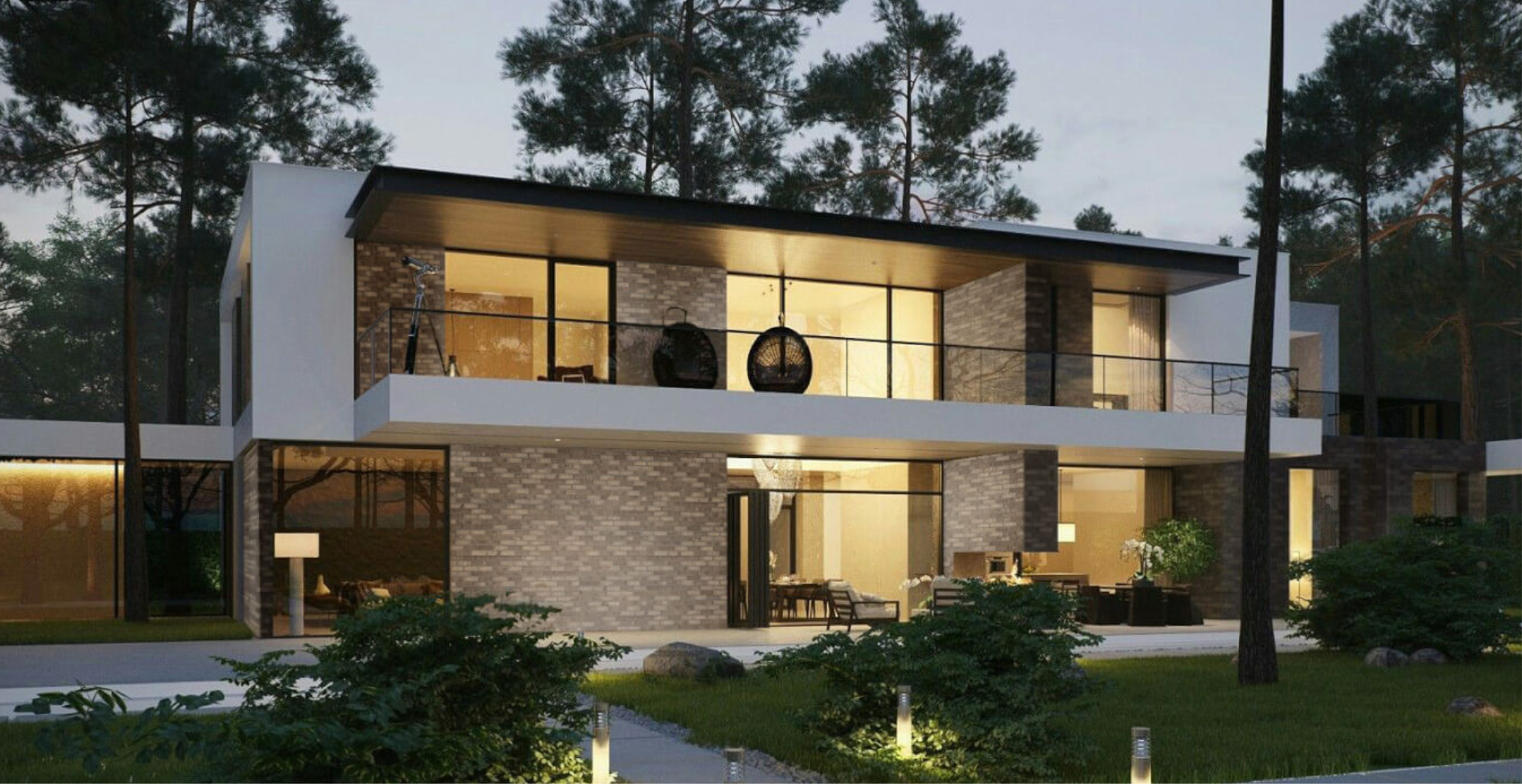 Modern house with glass windows and a brick facade surrounded by trees at dusk.