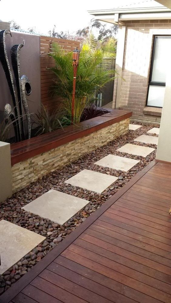Outdoor garden area with a wooden deck, stone pathways, and plants.